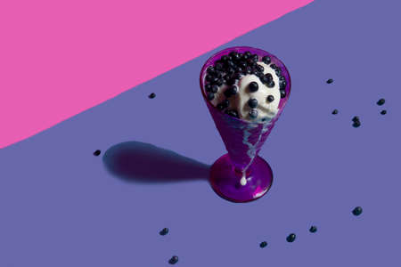 An amazing dessert of ice cream and blueberries in a purple vase with fresh blueberries on a bright background. isolated object. copy space, advertising - suitable for any field of activity. Very periの写真素材
