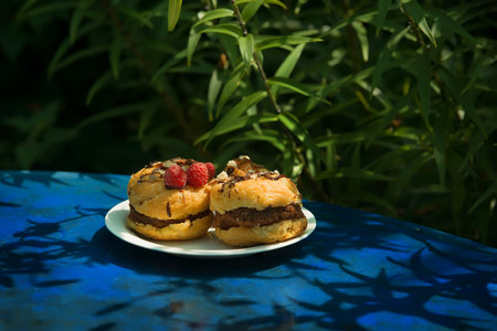 Cupcake Little sizes with raspberries on a blue background in the summer garden. summer mood. Confectionery blog, banner in a cafe and a restaurant. Menu of confectionery. homemade baking. interesting.の写真素材