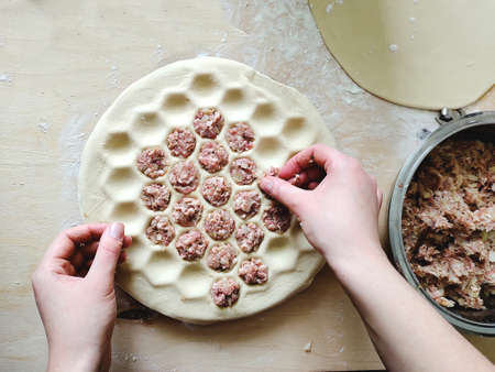 The hands of the cook spread the minced meat on the dumplings. the process of making dumplings. girl cooks for her family. home cooking, cooking at home. selective focus, soft light, copy spaceの写真素材