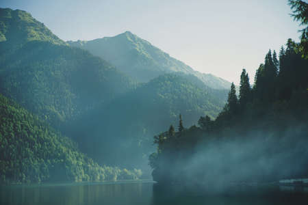 Magnificent view of a lake with a light morning fog.View of the lake in the mountains of the Caucasus.Stunning wildlife during sunrise.Amazing natural summer landscape creative image design.Copy spaceの写真素材