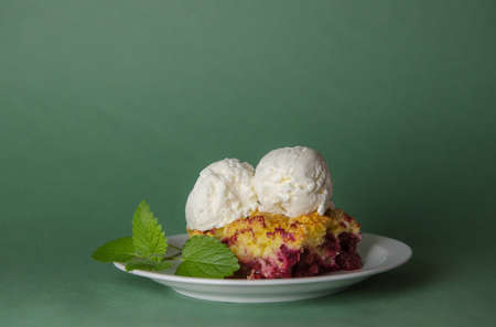 Delicious grated cherry and blueberry pie with vanilla ice cream balls on a delicate light green background.Horizontal selective focus.summer desserts. for confectionery menu and advertisingの写真素材