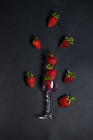 Fresh strawberries in a beautiful glass with flying berries on a dark background. tonic. selective focus. atmospheric summer background, mood. advertising of nightclubs and restaurantsの写真素材