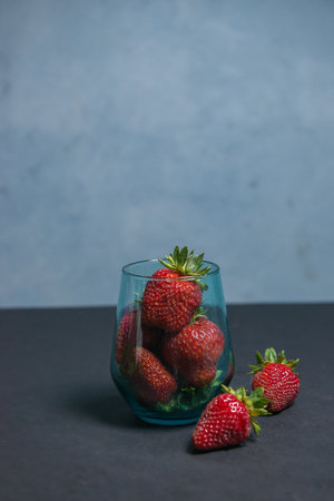 Fresh strawberries in a beautiful glass on a dark blue background. tonic. selective focus. atmospheric summer background, mood. advertising summer parties. promotional summer offers.の写真素材