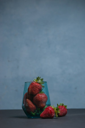 Fresh strawberries in a beautiful glass on a dark blue background. tonic. selective focus. atmospheric summer background, mood. advertising summer parties. promotional summer offers.の写真素材
