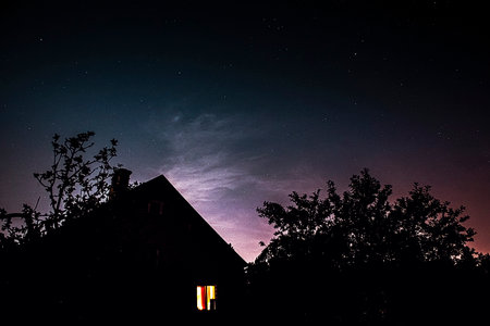 photo of a roof illuminated by moonlight and the starry sky above it. stars, roof, dream. atmospheric photography of the starry sky. take a walk on the roofs and admire the stars. soft focusの写真素材