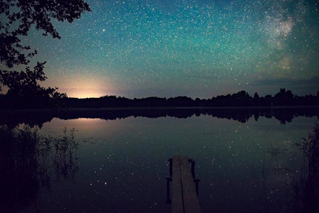 Stars in the night sky, reflected at night in the lake. The Milky Way and a mountain lake with reflected stars. A mystical picture of a mysterious lake with mermaids. night shooting at long exposureの写真素材