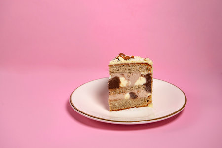 Festive banana cake in white chocolate, decorated with nuts, cookies and chocolate on a pink...