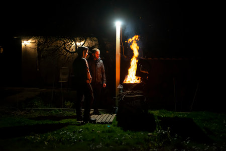 A father and son build a barbecue fire on their plot to cook dinner on an open fire, hey look at the fire and talk.the concept of family values. advertising of insurance companies' services.copy spaceの写真素材