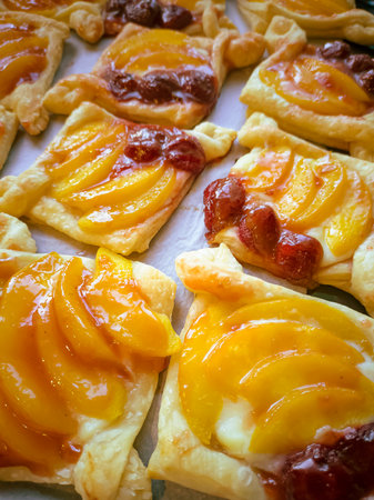 Homemade puff pastry with red strawberries and mangos sprinkled with white icing sugar on a beige wooden board. baking in close-up. culinary background of the finished product. fragrant and appetizingの写真素材