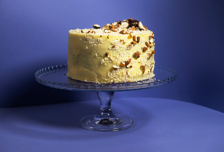 Festive banana cake in white chocolate, decorated with nuts, cookies and chocolate on a purple background. exclusive pastries according to the author's recipes. for a culinary blog and a pastry shopの写真素材