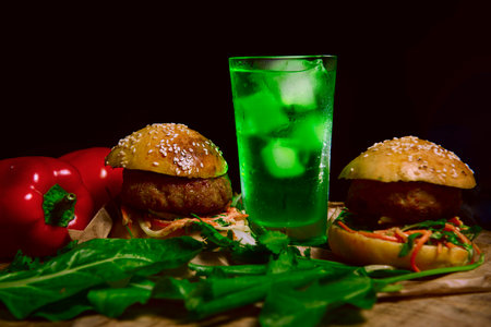 hamburger and mojito lemonade with ice, with herbs and vegetables on a dark background. Bright vegetables in the photo, green lemonade with ice, attract attention and excite the appetite.Advertisementの写真素材
