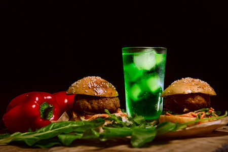 Homemade hamburger and mojito lemonade with ice, herbs and vegetables on a dark background. Restaurant advertising and menu.Delicious hamburger cooked at home.Delicious poster for the dining roomの写真素材