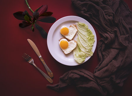 For Breakfast on Valentine's day serves scrambled eggs in the shape of a heart with lettuce. top viewの写真素材