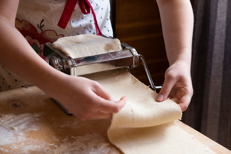Automation of the Process of Working with the test at home.The girl rolls out the dough using a pasta dough rolling machine. it is easy and not difficult to Cook Sfogliatelle. real peopleの写真素材