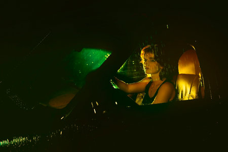 Night riding in the pouring rain. A woman is sitting in a car against the background of city lights. evening nighttime. People, driving, transport problems, car accidents, people's emotions. insuranceの写真素材