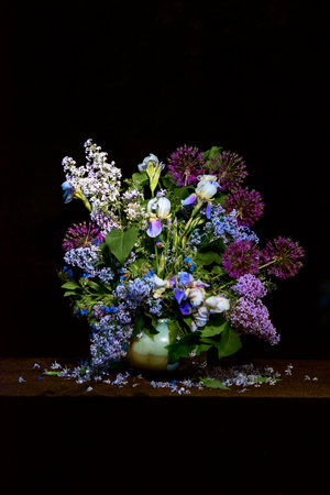 A beautiful bouquet of lilac and different colors of blue shades on a black background. Fancy floral arrangement of lilac and wildflowers. floral design. stylish poster with non-standard floral designの写真素材