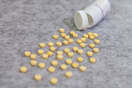 Yellow pills scattered gray backgroundの写真素材
