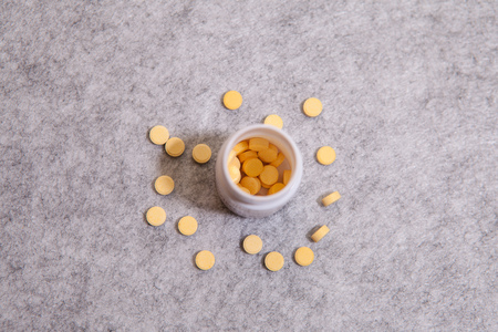 Pill bottle spilling pills onto surface isolated on a grey backgroundの写真素材