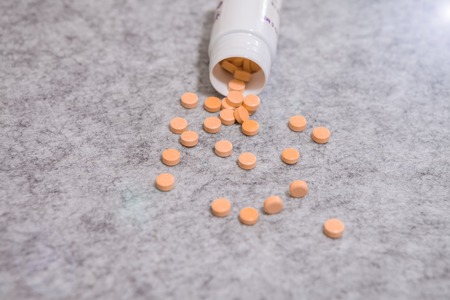 Pill bottle spilling pills onto surface isolated on a grey backgroundの写真素材