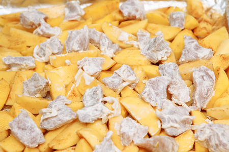 Sliced potatoes with meat, raw on a baking sheet, cookingの写真素材