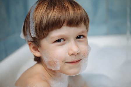 Boy in a bath with foam, shampoo, cheerful, smilingの写真素材