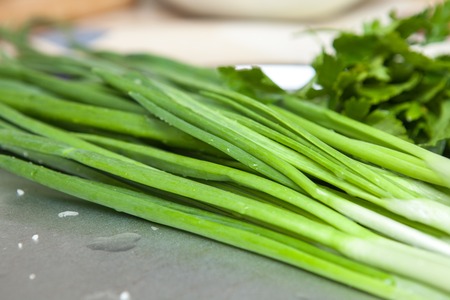 Fresh green onion on the kitchen table, close-upの写真素材