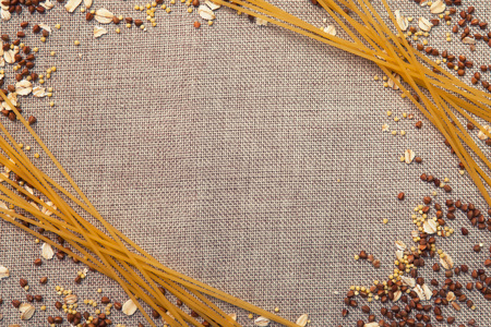 Background wallpaper, pasta spaghetti, croup, buckwheat, rice, oatmeal, cereal, scattered on fabric.の写真素材