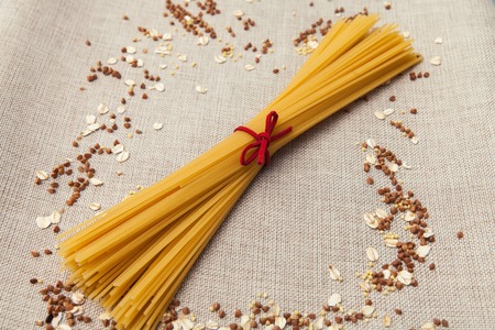 Background wallpaper, pasta spaghetti, croup, buckwheat, rice, oatmeal, cereal, scattered on fabric.の写真素材