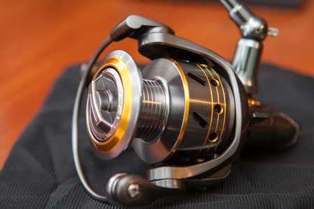 Reel for fishing rods, close up on wood background. Fishing coil close-up.の写真素材