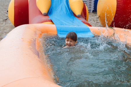 A small boy is happily bathed in an inflatable pool.の写真素材