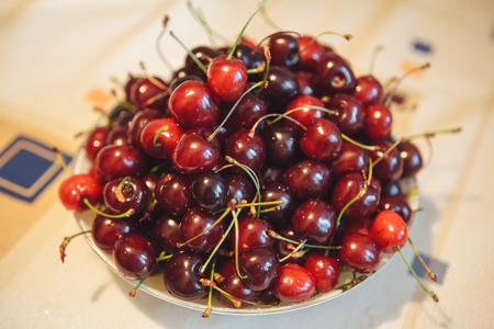 The berry of ripe cherry on the table in a plate.の写真素材