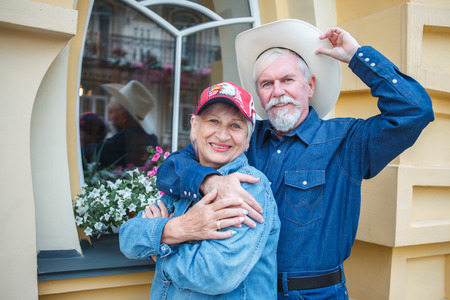Happy friendly senior couple posing arm in arm with their faces touching smiling at the cameraの写真素材