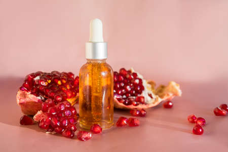 Composition with natural cosmetic oil and pomegranate on light background