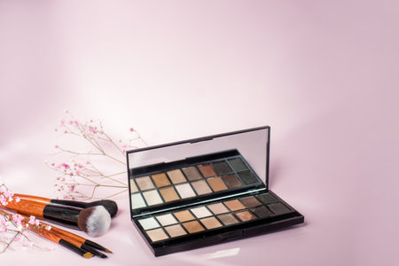 eye makeup brushes lie near a palette of eyeshadows on a pink backgroundの写真素材