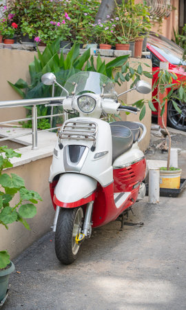 White and orange moped parked on the street.の写真素材