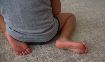 Child sitting on the lap on the floor, feet on the carpet close-up .Autism concept,の写真素材