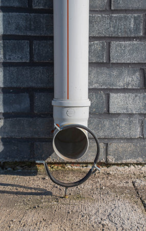 closeup shot of a plastic damaged rain pipe on the wallの写真素材