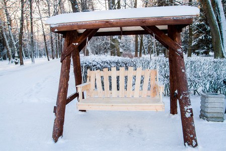 Wooden swing bench in the Park in winterの写真素材
