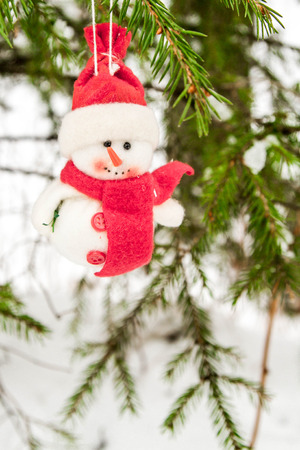 Toy snowman hanging on a snow-covered treeの写真素材