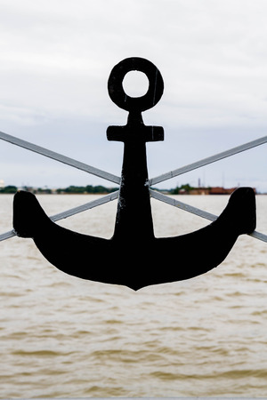 Black metal anchor on the gray fenceの写真素材