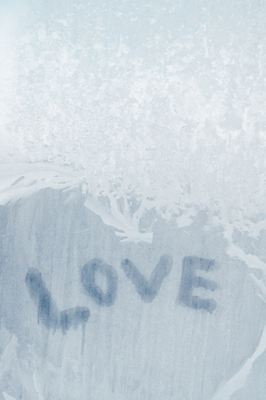 Love inscription on the frozen window in winter patterns in winterの写真素材