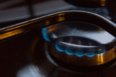 Gas stove with burning orange and blue fire on it