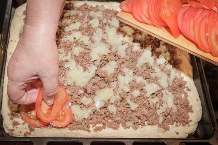 Cooking pizza pie with meat and vegetables under cheeseの写真素材