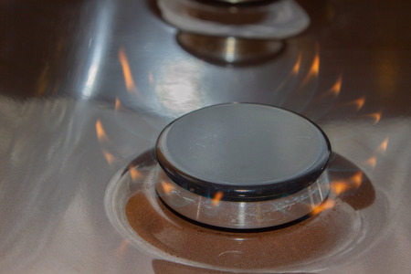Gas stove with burning orange and blue fire on itの写真素材