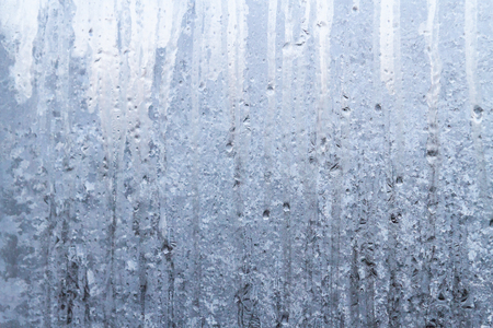 The frozen drops on the patterned frosty winter windowの写真素材