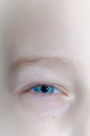 Baby blue beautiful, brooding eyes of a boyの写真素材