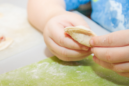 Small boy sculpts a homemade ravioli at homeの写真素材