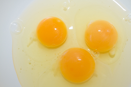 Three broken chicken eggs in a white mixing bowlの写真素材