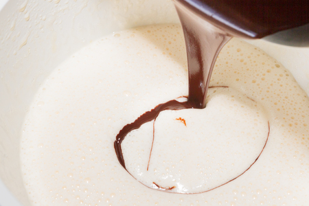 Cooled melted dark chocolate poured in the beaten eggs with sugarの写真素材