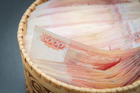 A lot of banknotes worth five thousand rubles are in a round wooden wicker box.の写真素材